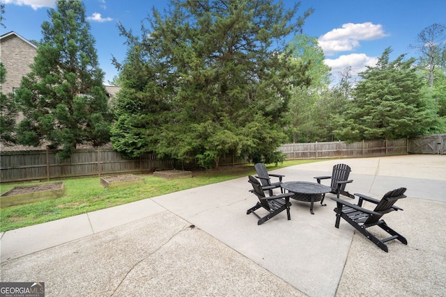 view of patio with a fenced backyard, a garden, and a fire pit