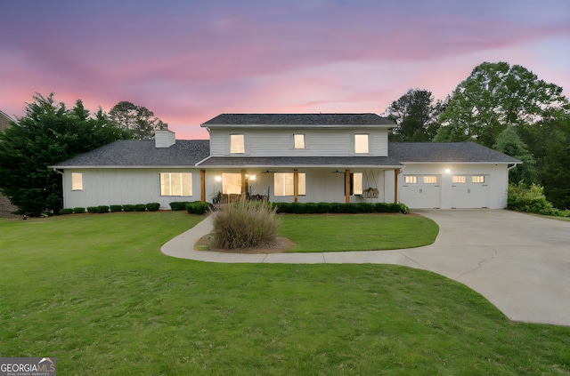 traditional-style house featuring board and batten siding, a chimney, a front yard, a garage, and concrete driveway