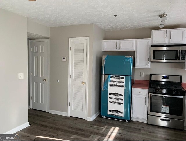 2353 Wellington Cir, Lithonia, GA 30058 - kitchen featuring white cabinets, a textured ceiling, appliances with stainless steel finishes, and dark wood finished floors