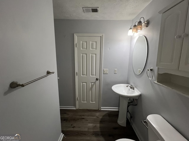 2353 Wellington Cir, Lithonia, GA 30058 - bathroom featuring visible vents, wood finished floors, toilet, baseboards, and a textured ceiling