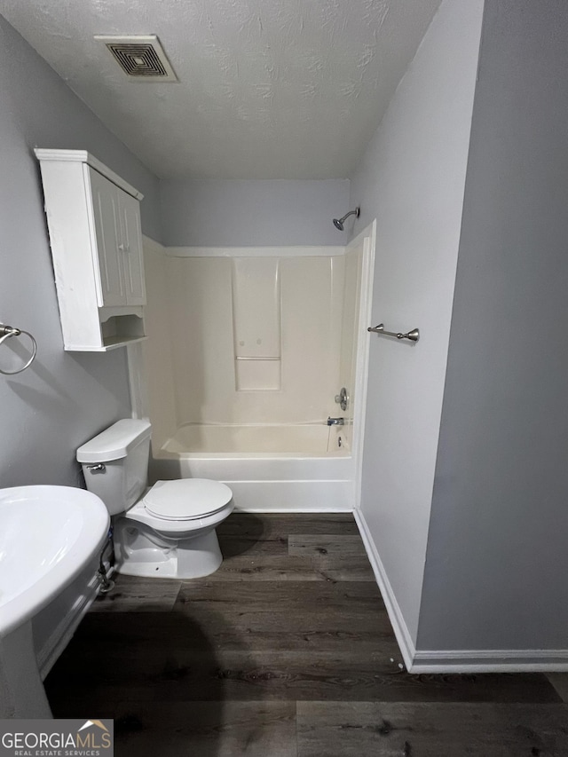 2353 Wellington Cir, Lithonia, GA 30058 - bathroom featuring bathtub / shower combination, toilet, a textured ceiling, wood finished floors, and visible vents