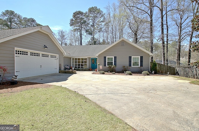 ranch-style house featuring fence, roof with shingles, an attached garage, a front yard, and driveway