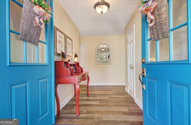 entrance foyer with baseboards, a textured ceiling, and wood finished floors