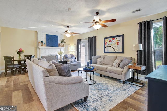 living area with visible vents, wood finished floors, baseboards, ceiling fan, and a textured ceiling
