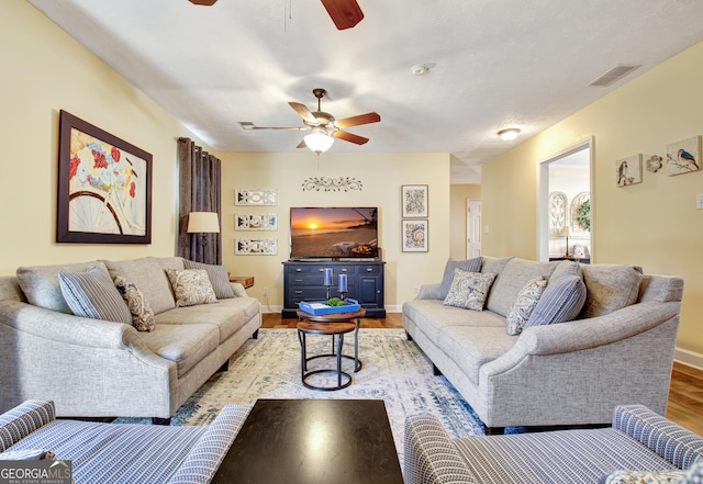 living room with a ceiling fan, baseboards, visible vents, and light wood-style floors