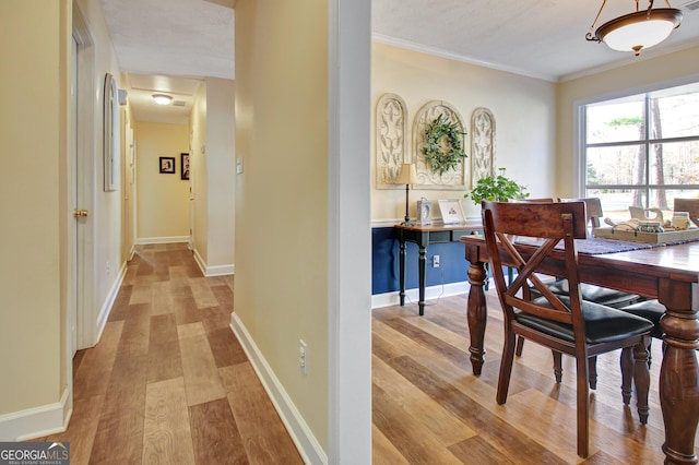 dining space featuring baseboards, ornamental molding, and light wood finished floors