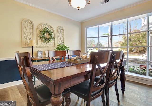 dining room featuring baseboards, ornamental molding, wood finished floors, and visible vents