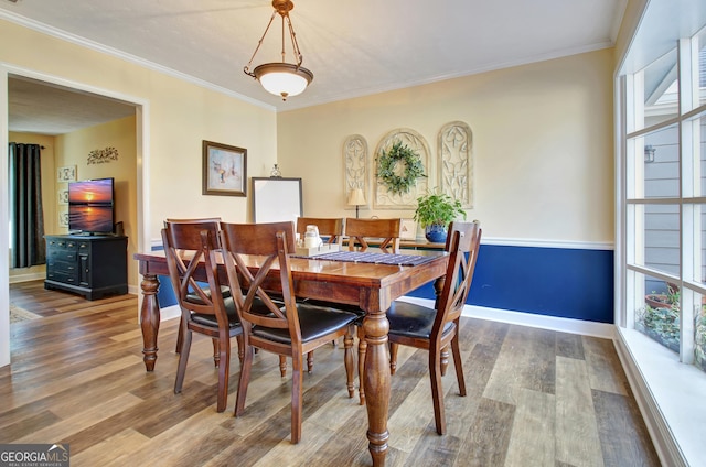 dining area with baseboards, ornamental molding, and wood finished floors