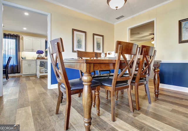 dining area with visible vents, ornamental molding, light wood-style floors, baseboards, and a ceiling fan