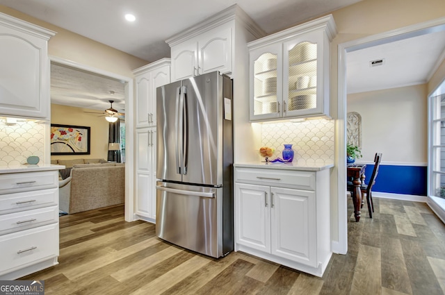 kitchen with freestanding refrigerator, decorative backsplash, white cabinets, and light wood-style flooring