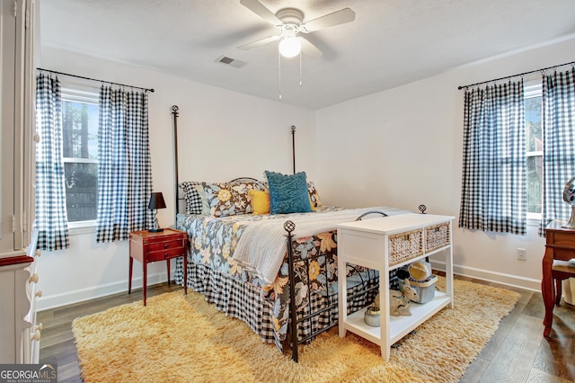 bedroom featuring ceiling fan, baseboards, visible vents, and wood finished floors