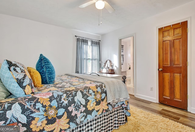 bedroom featuring ceiling fan, baseboards, ensuite bathroom, and wood finished floors
