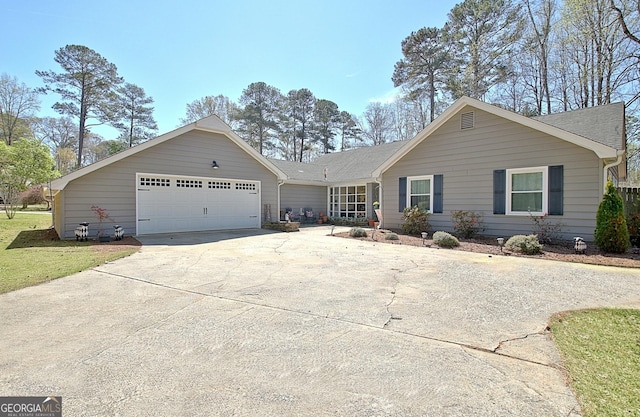 ranch-style house with an attached garage, a shingled roof, and concrete driveway