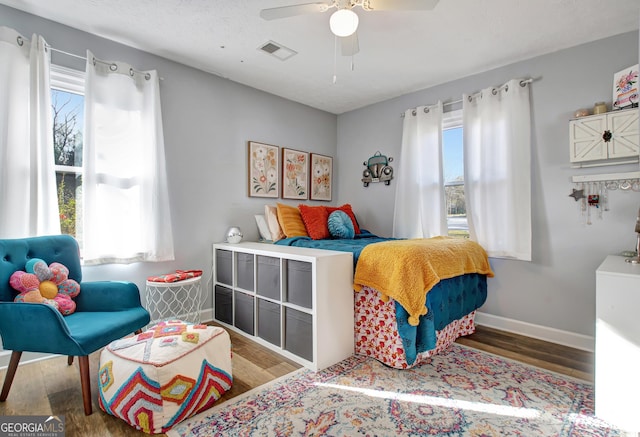 bedroom featuring a ceiling fan, baseboards, visible vents, and wood finished floors