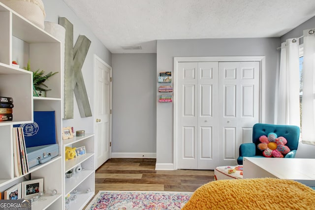 bedroom featuring a closet, baseboards, a textured ceiling, and wood finished floors