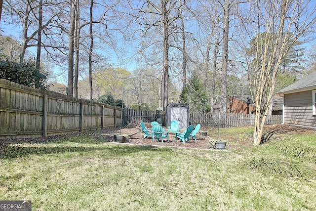 view of yard with an outdoor structure, a fenced backyard, and a storage shed