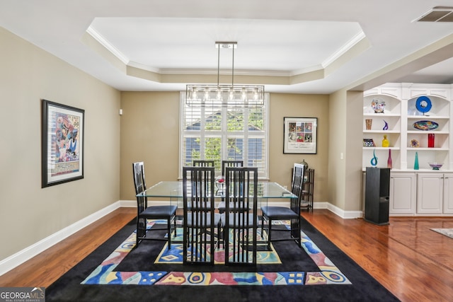 dining area featuring baseboards, ornamental molding, a tray ceiling, and dark wood-type flooring
