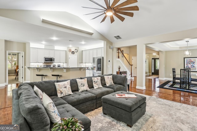 living area featuring stairs, visible vents, lofted ceiling, and light wood-style floors