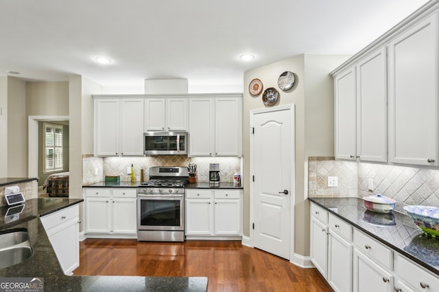 kitchen with dark wood-type flooring, dark stone counters, tasteful backsplash, and stainless steel appliances