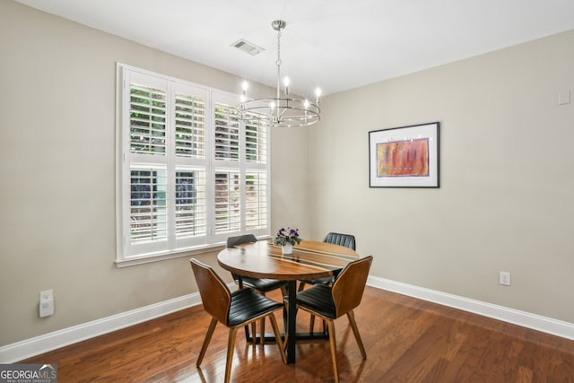 dining space with baseboards, visible vents, an inviting chandelier, and wood finished floors