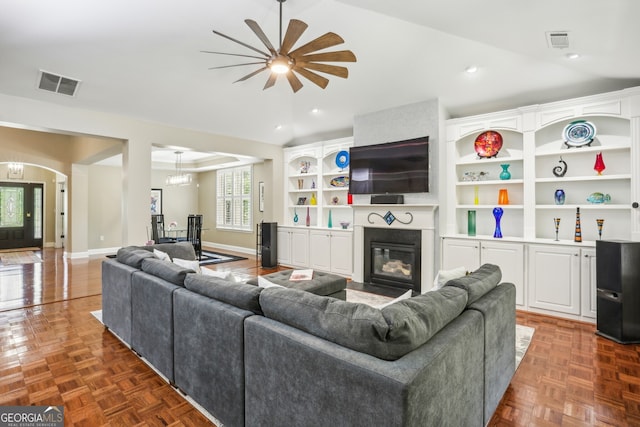living room featuring a glass covered fireplace, baseboards, a ceiling fan, and visible vents