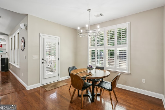 dining space with wood finished floors, plenty of natural light, a chandelier, and visible vents