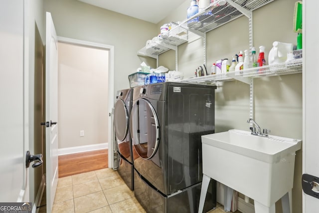 laundry room with laundry area, independent washer and dryer, a sink, baseboards, and light tile patterned floors