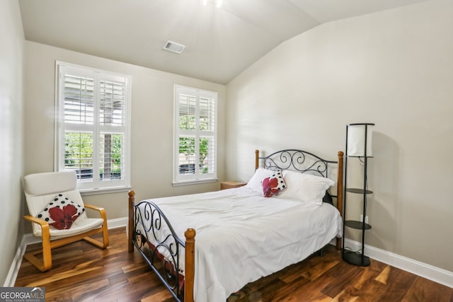 bedroom with baseboards, visible vents, wood finished floors, and lofted ceiling
