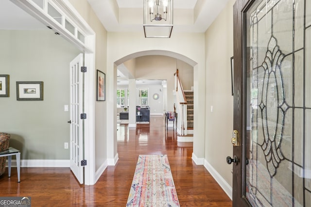 entryway with wood finished floors, baseboards, stairway, french doors, and arched walkways