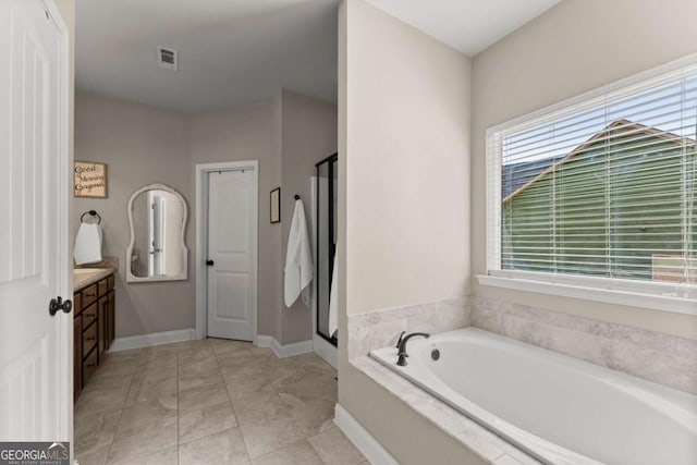 1929 Windstone Pl, Winder, GA 30680 - bathroom with vanity, baseboards, visible vents, a garden tub, and a stall shower