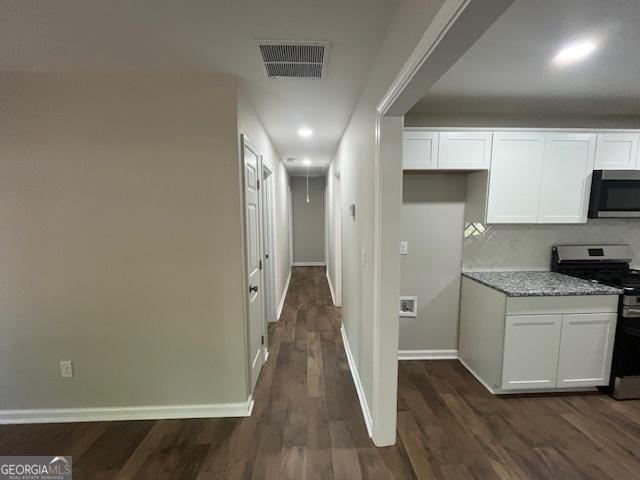 kitchen featuring stainless steel appliances, dark wood-style floors, white cabinetry, and visible vents
