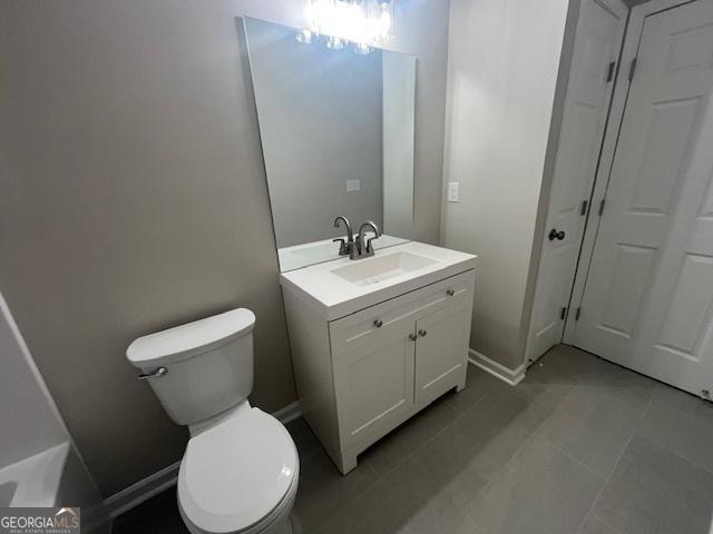 bathroom with toilet, tile patterned floors, and vanity