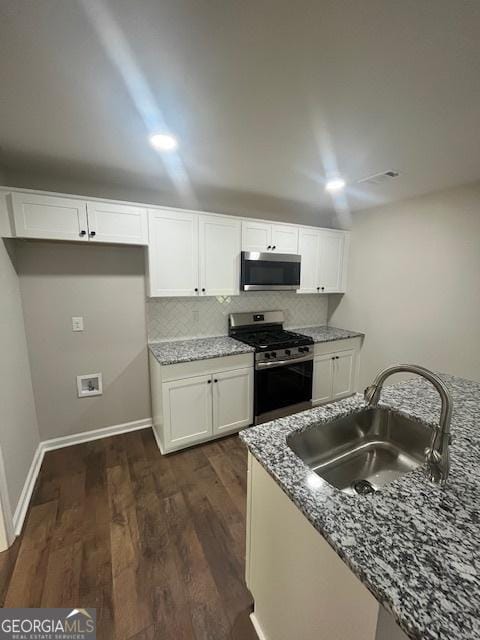 kitchen with white cabinets, a sink, stainless steel appliances, decorative backsplash, and dark wood-type flooring