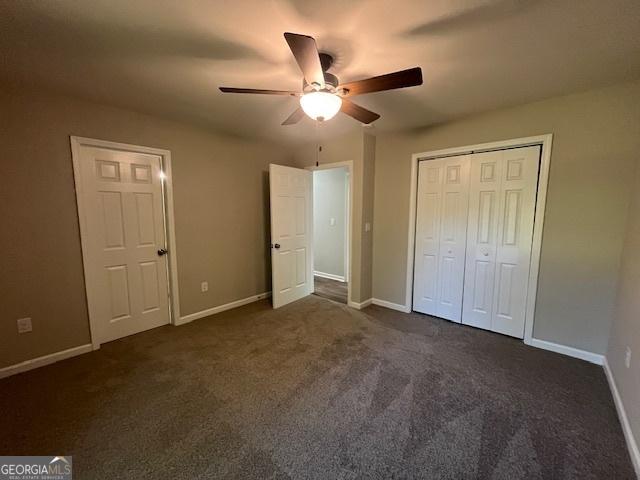 unfurnished bedroom with a ceiling fan, baseboards, a closet, and dark colored carpet