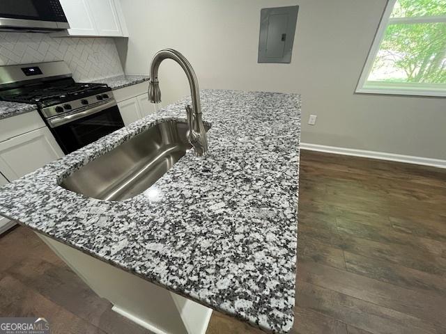 room details with baseboards, white cabinetry, light stone counters, a sink, and stainless steel appliances