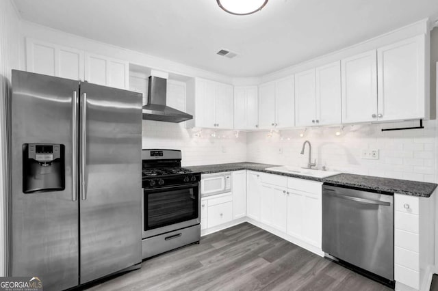 2551 Park Rd SE, Smyrna, GA 30080 - kitchen featuring wall chimney range hood, white cabinets, tasteful backsplash, a sink, and appliances with stainless steel finishes
