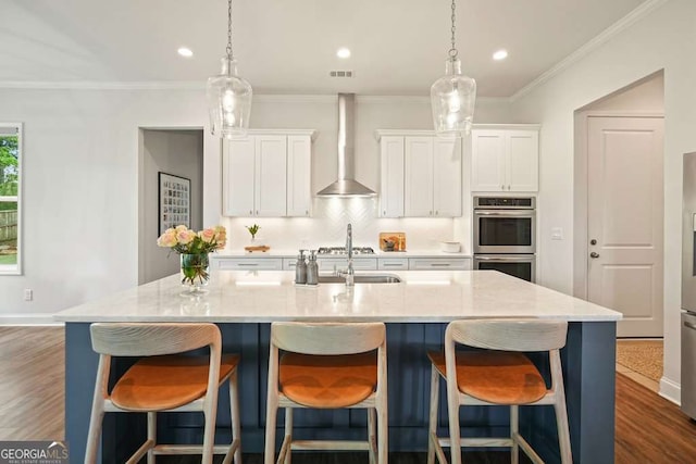 242 Fieldbrook Xing, Canton, GA 30115 - kitchen with stainless steel double oven, white cabinetry, a kitchen island with sink, and wall chimney range hood