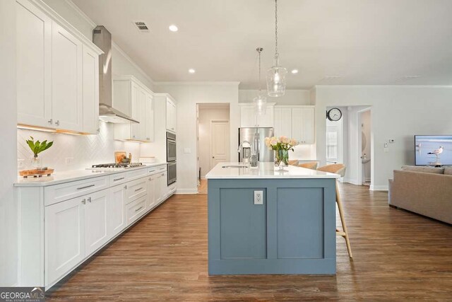 242 Fieldbrook Xing, Canton, GA 30115 - kitchen featuring appliances with stainless steel finishes, tasteful backsplash, open floor plan, wall chimney exhaust hood, and an island with sink