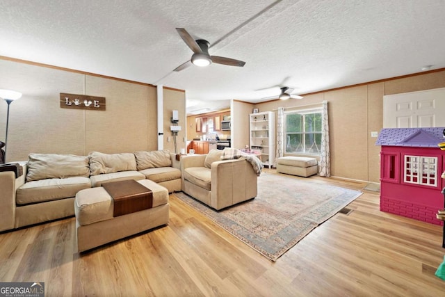 living area featuring crown molding, a textured ceiling, ceiling fan, and wood finished floors