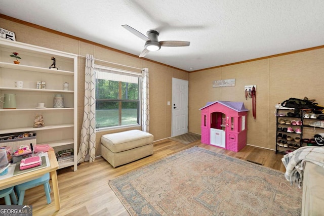 rec room with ornamental molding, a textured ceiling, ceiling fan, and wood finished floors