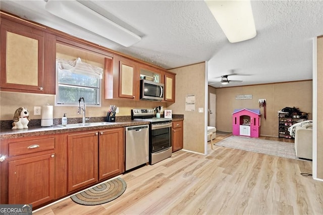 1575 Davis Rd W, Fairmount, GA 30139 - kitchen featuring appliances with stainless steel finishes, a sink, brown cabinets, light wood-style flooring, and a textured ceiling
