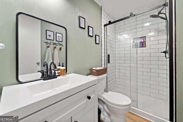 bathroom with vanity, toilet, wood finished floors, and a stall shower