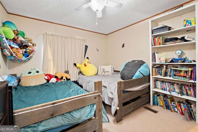 bedroom with crown molding, a textured ceiling, carpet, and a ceiling fan