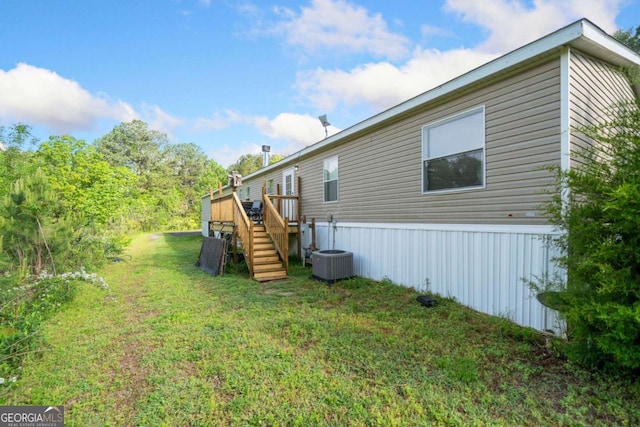 rear view of house with a lawn, a wooden deck, stairs, and central AC unit