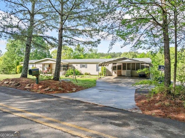 ranch-style home featuring a sunroom, a detached carport, and driveway