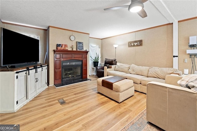 1575 Davis Rd W, Fairmount, GA 30139 - living area featuring ceiling fan, crown molding, light wood-style flooring, a textured ceiling, and a glass covered fireplace