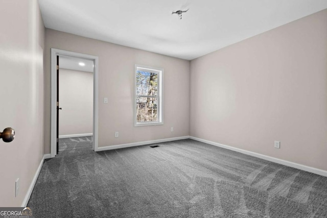 empty room with baseboards and dark colored carpet