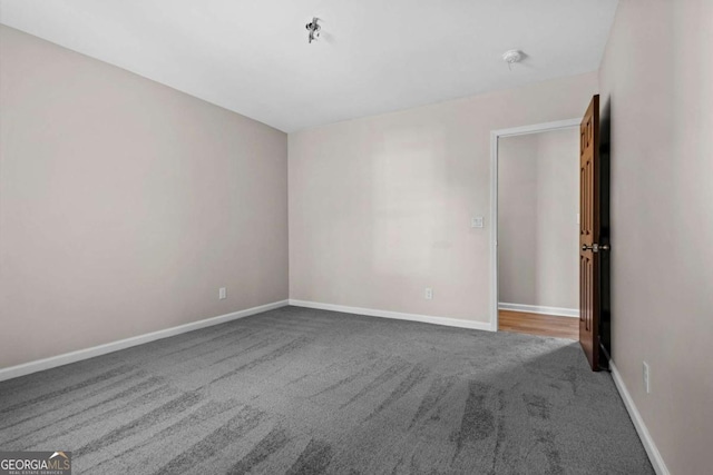 unfurnished room with carpet flooring and baseboards