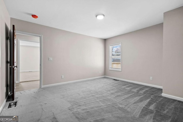 carpeted spare room featuring baseboards and visible vents