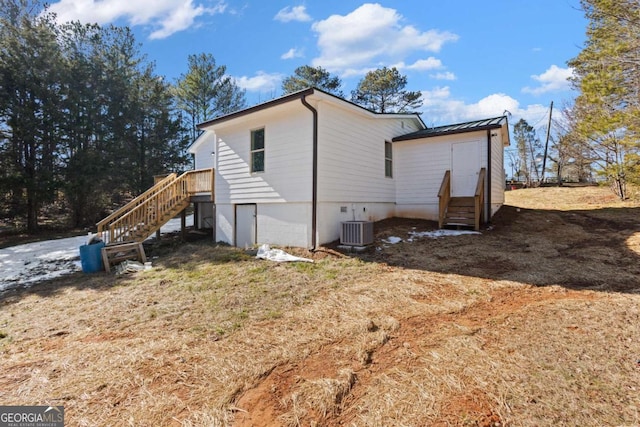 view of home's exterior with a standing seam roof, metal roof, cooling unit, stairs, and entry steps